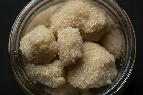 Glass jar filled with dry sifted cannabis trichome heads showing granular white crystalline texture illustrating isolated trichome starting material for solventless rosin pressing.